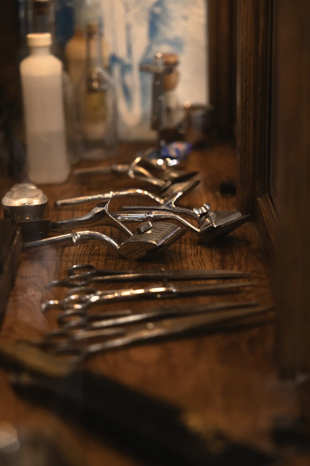 Hand clippers, shears and combs laid out along the wooden counter